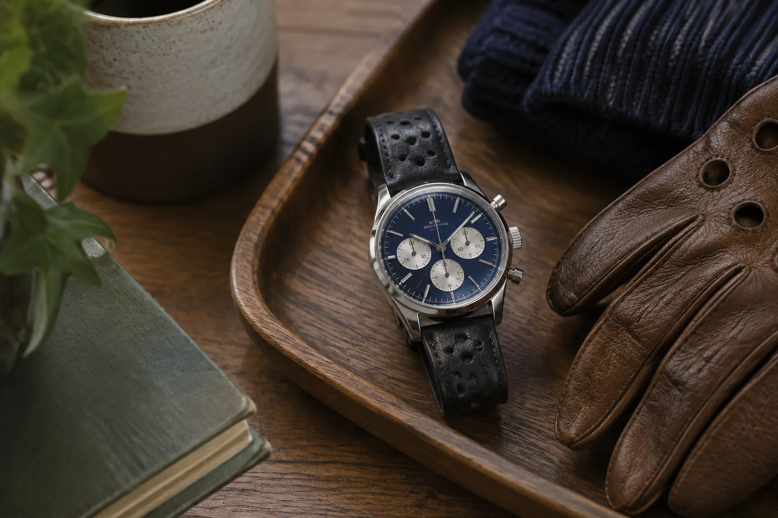 A blue-dial chronograph beside driving gloves and navy knitwear, showing the everyday appeal of motorsport watches
